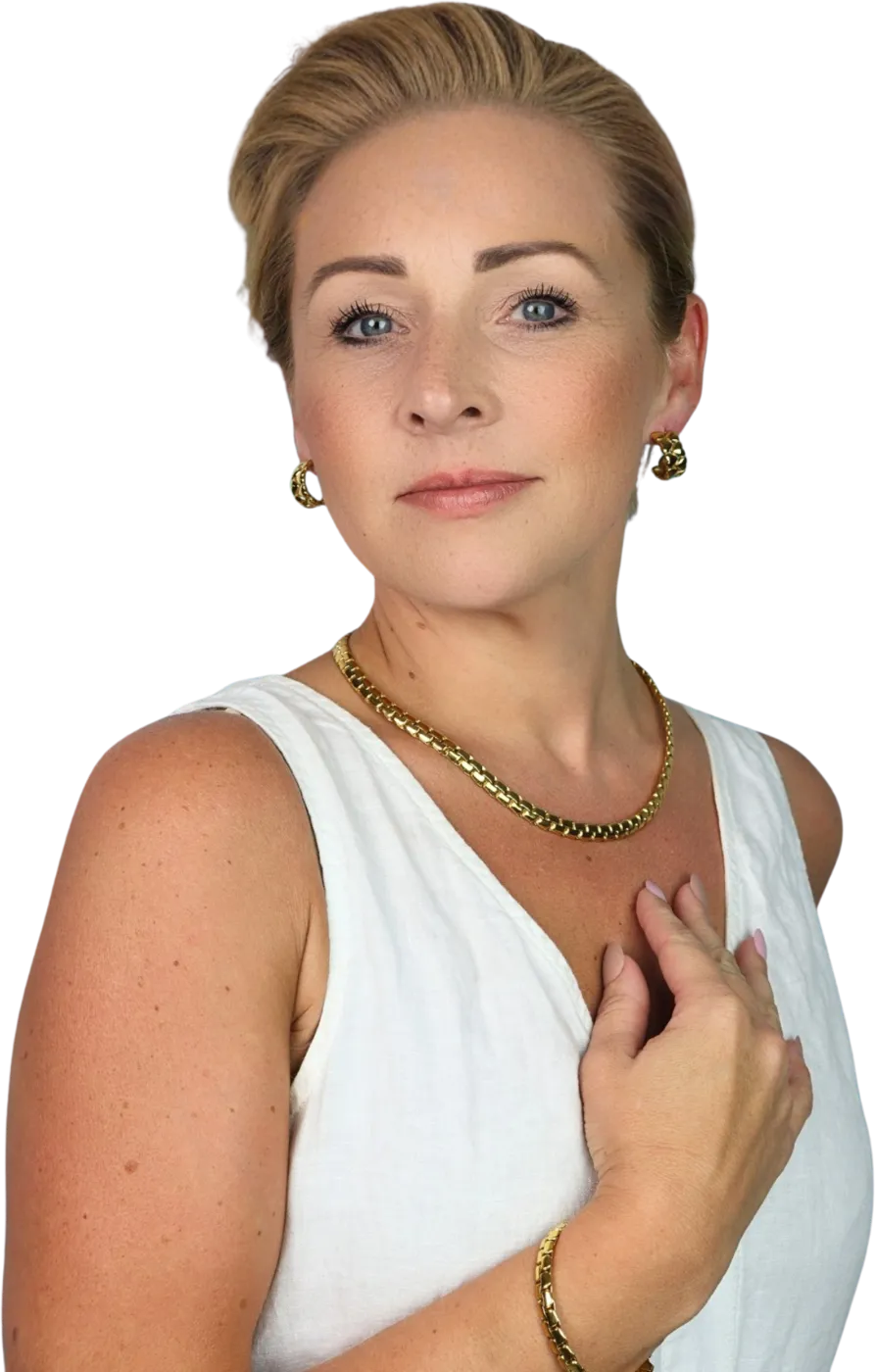 Charlotte Smith smiling, hand resting at her collarbone, in a white linen top with gold jewellery